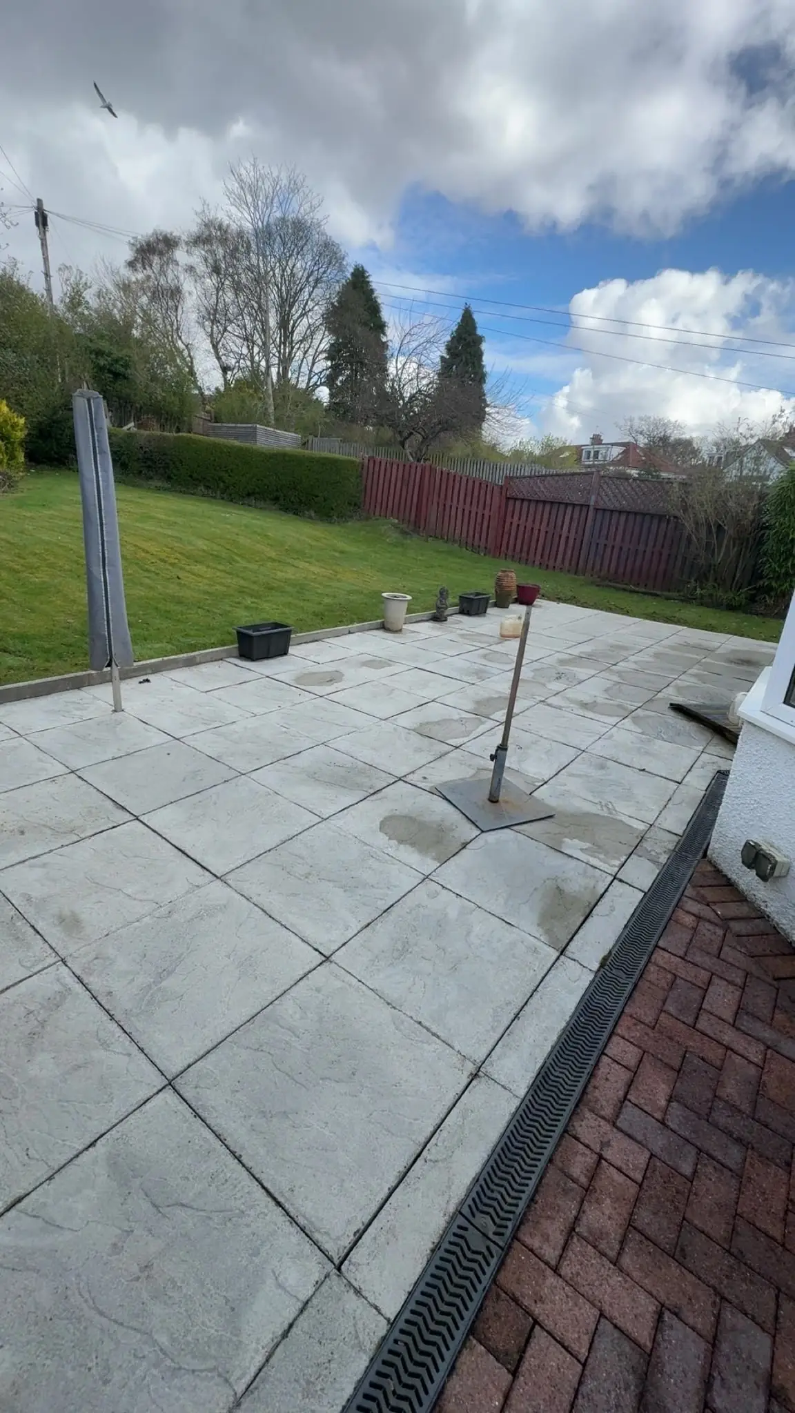 The same patio pressure washed clean, the drain channel and paviors beside it