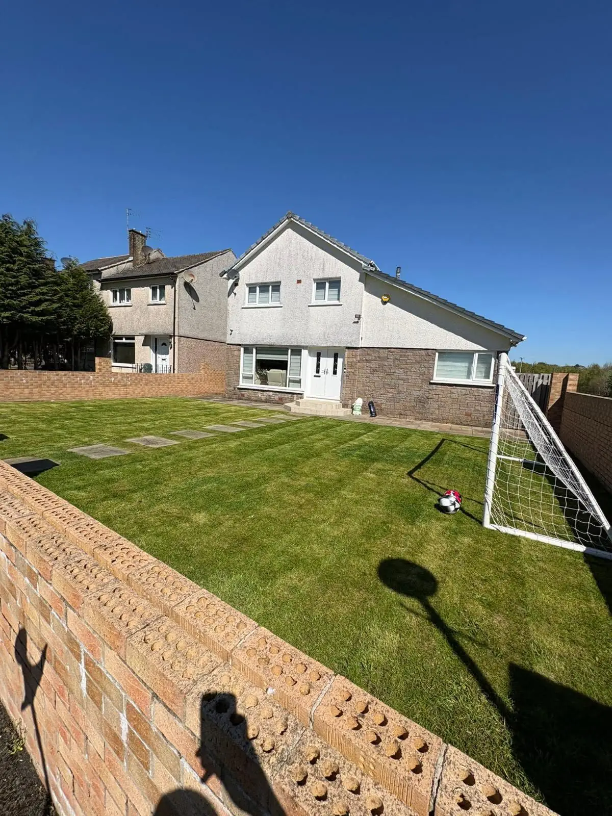 A front lawn behind a low brick wall